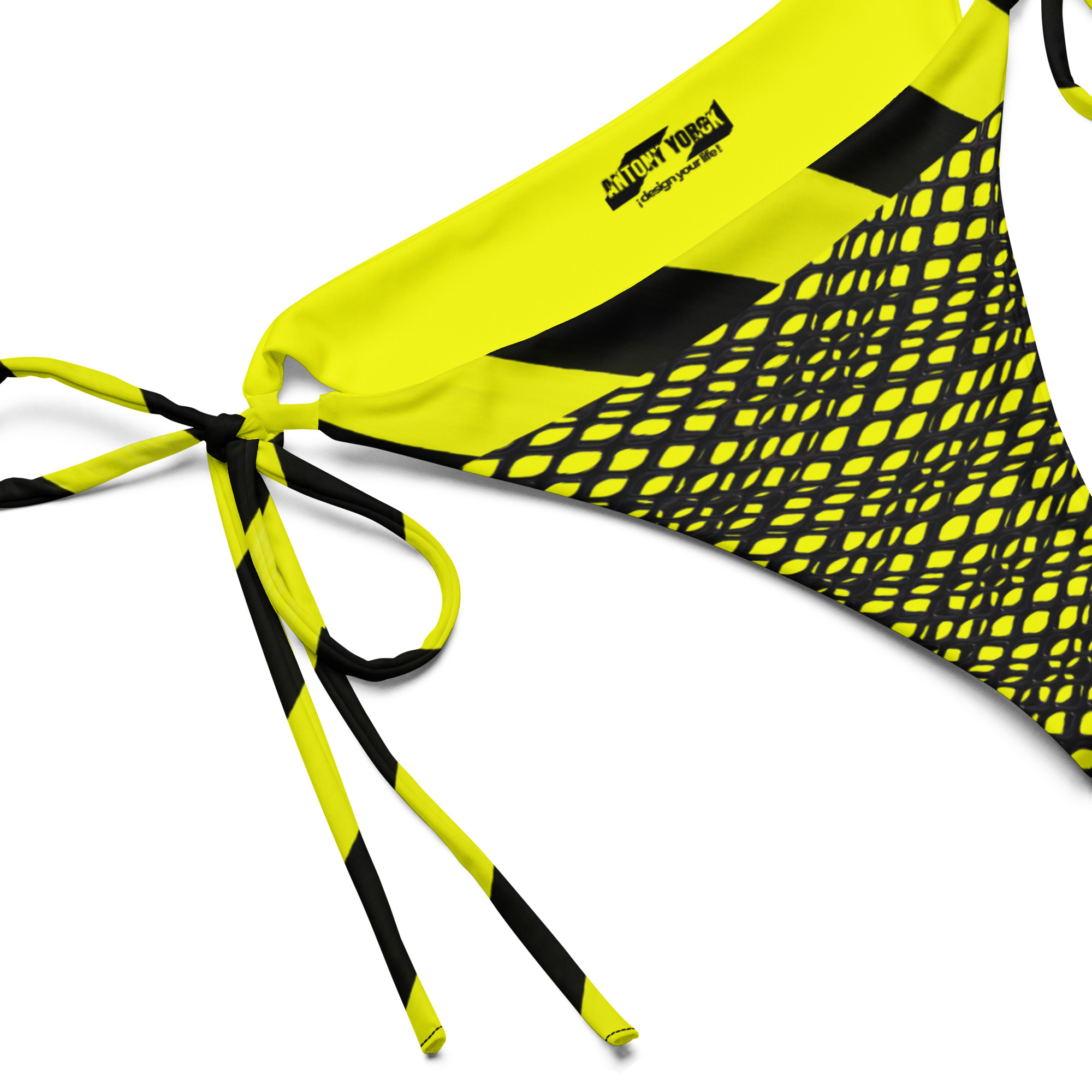 Designer String Bikini-Unterteil PROHIBITED NOBILITY Edition 03 4 Nahaufnahme des Designer String Bikini-Unterteils Edition 03 mit Fokus auf den schwarzen ANTONY YORCK Logo-Print, das kinetische Gittermuster und die präzise verarbeiteten neongelben Bindebänder.